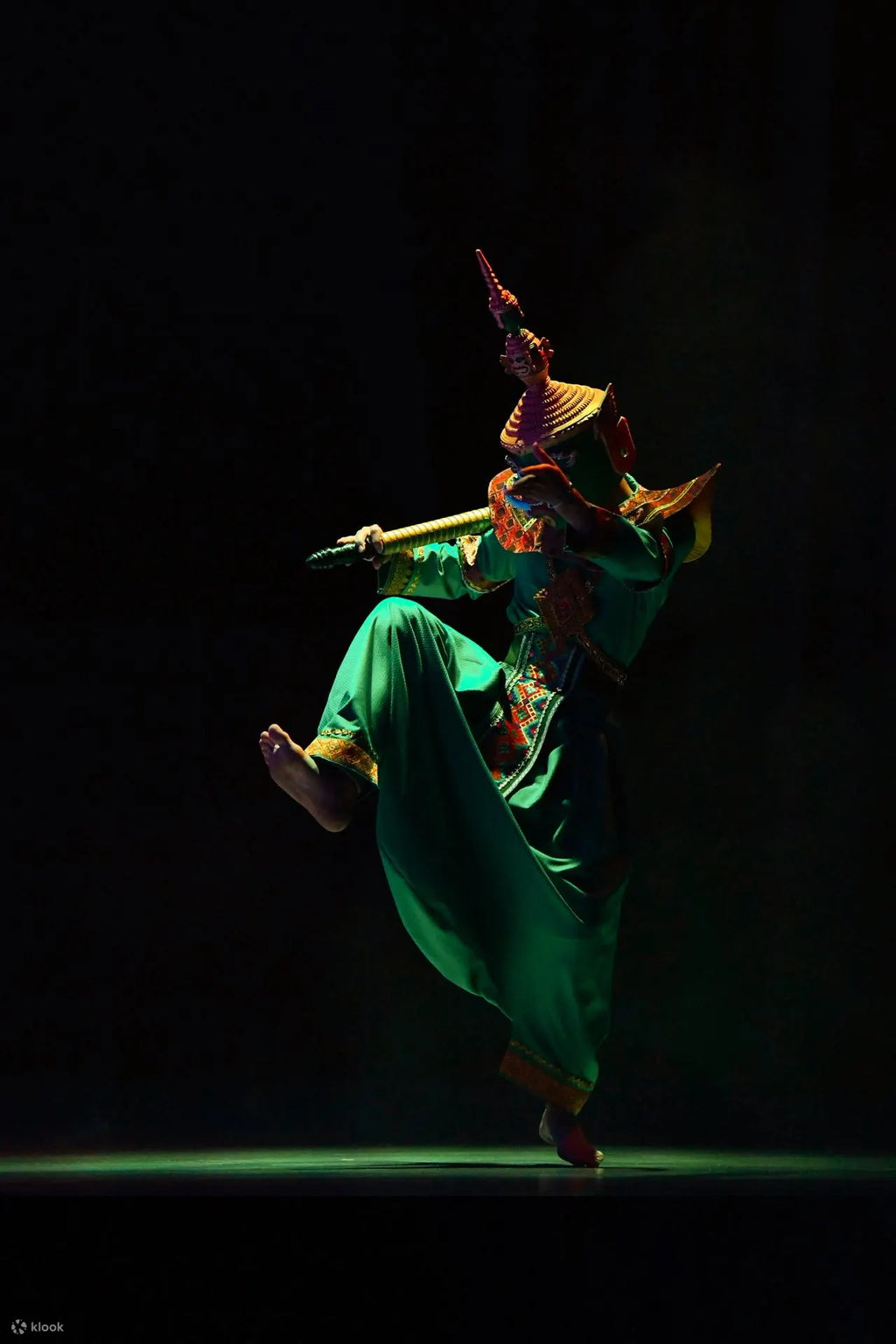 Dancer in colorful costume performing on a dark stage